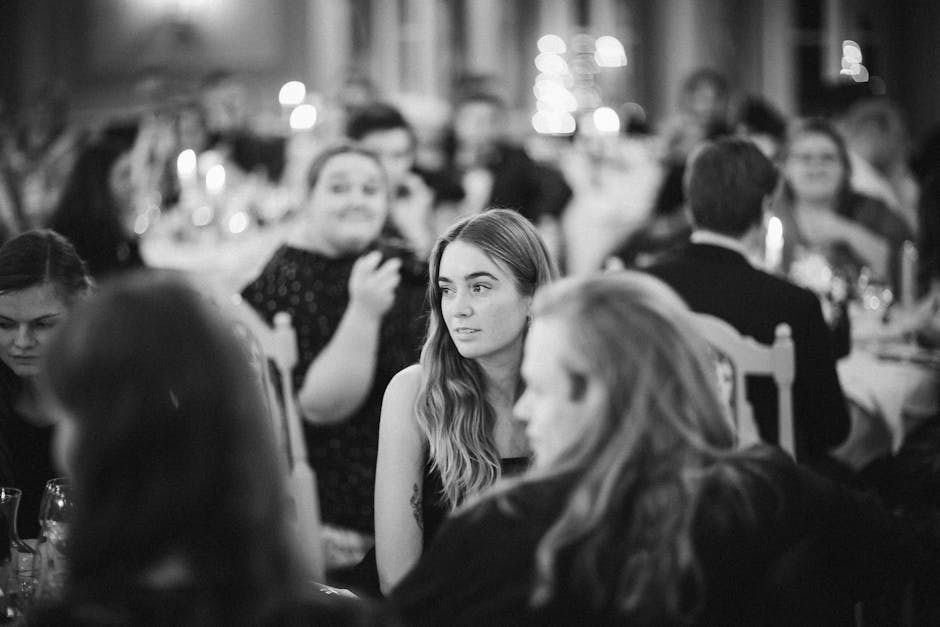 Monochrome photo of people at an elegant dinner gathering with blurred background.